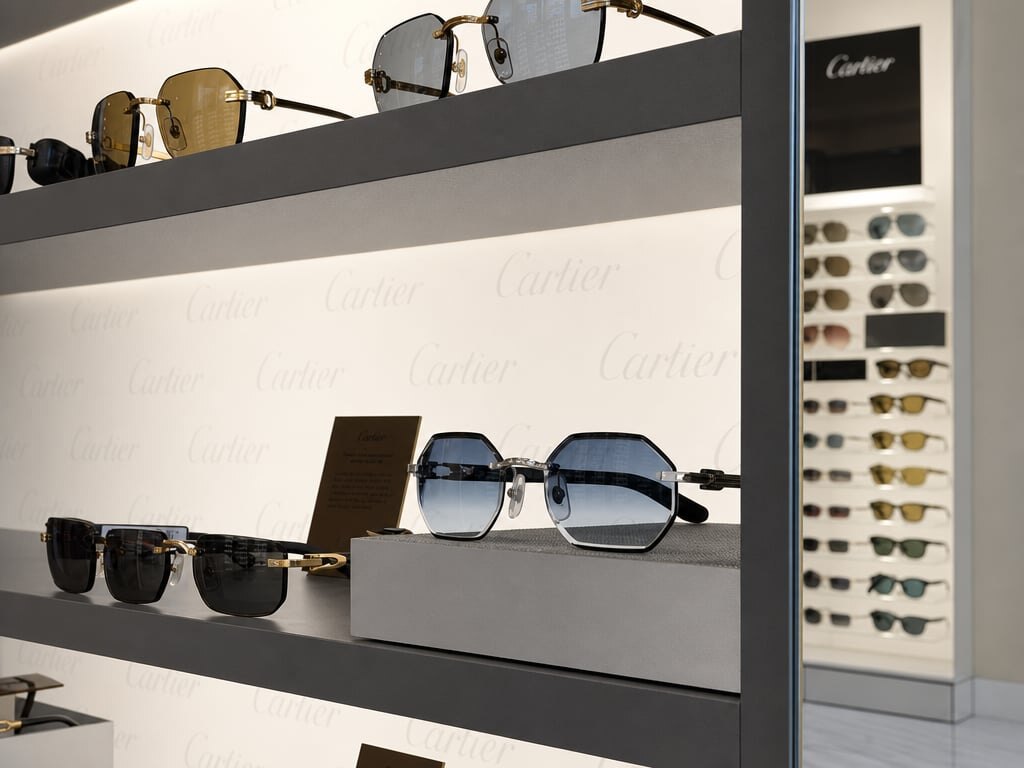 Dettaglio di montature Cartier rimless in oro su parete brandizzata
