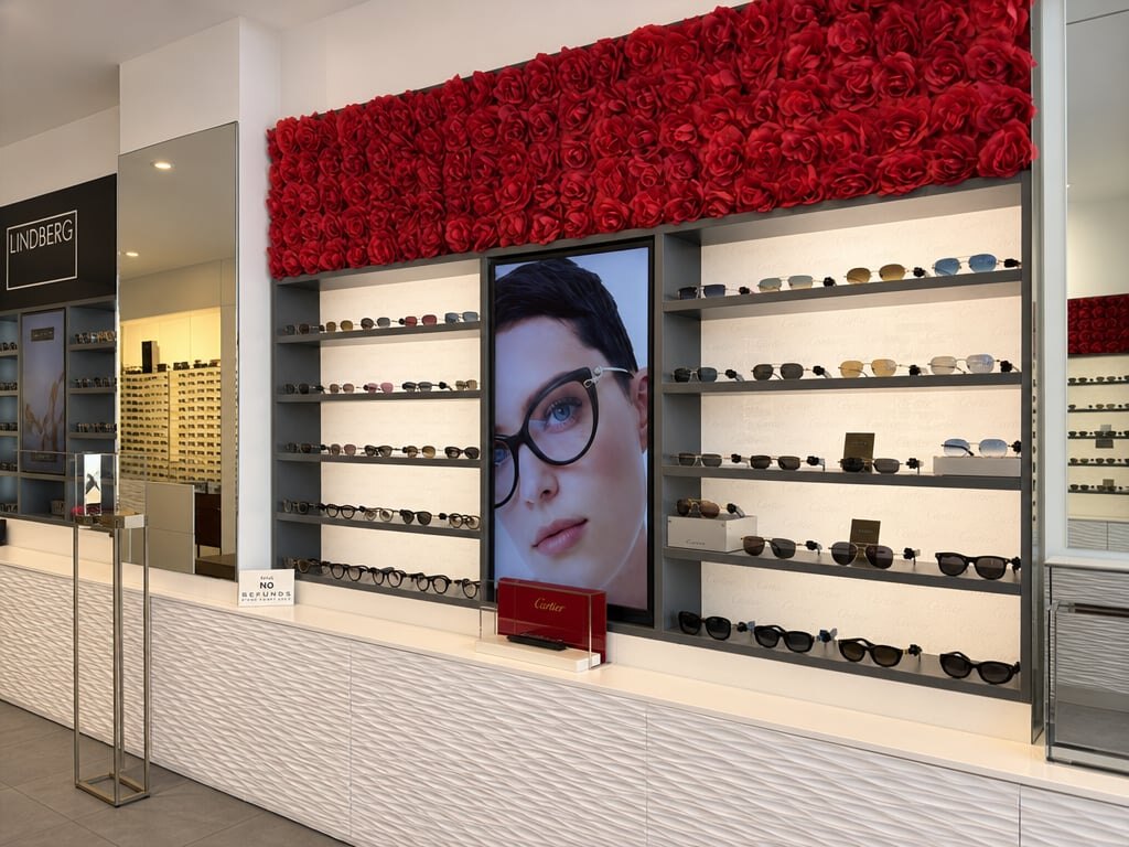 La parete di rose rosse sopra gli scaffali di montature nella boutique Giornalfoto